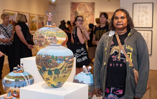 female artist stands in front of terracotta painted pot