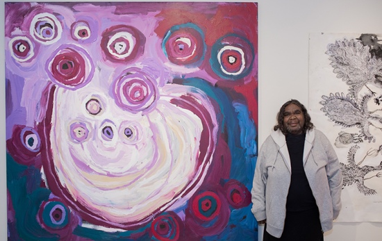 female artist stands in front of purple painting