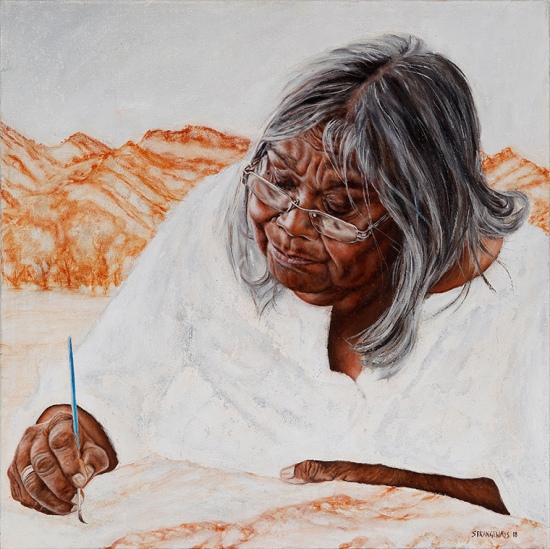 aboriginal women painting with orange hills behind her